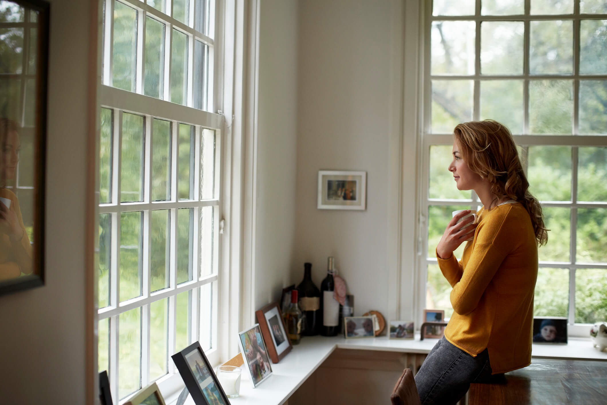 woman standing inside house looking out the window
