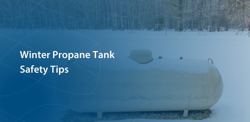 Tan outdoor propane tank sitting in a snow covered yard with woods in the background